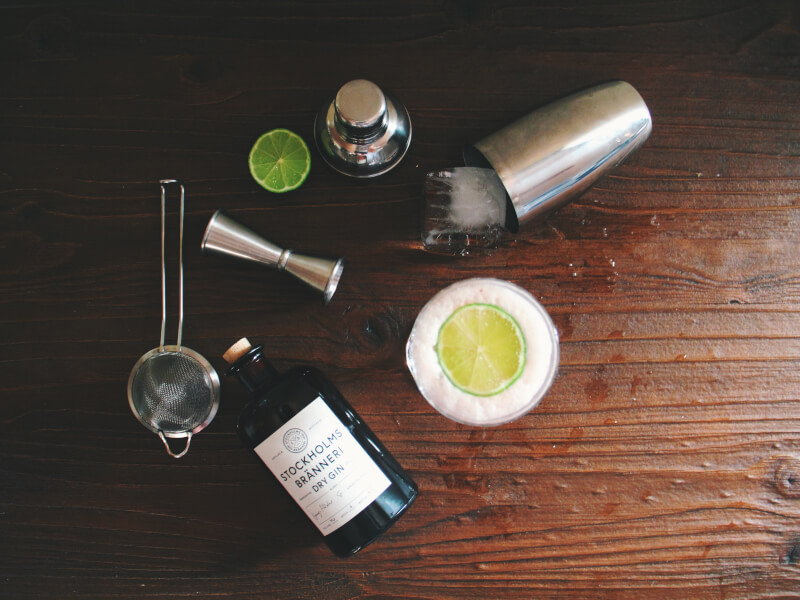 A set of materials needs to make a cocktail spread over a wooden table.